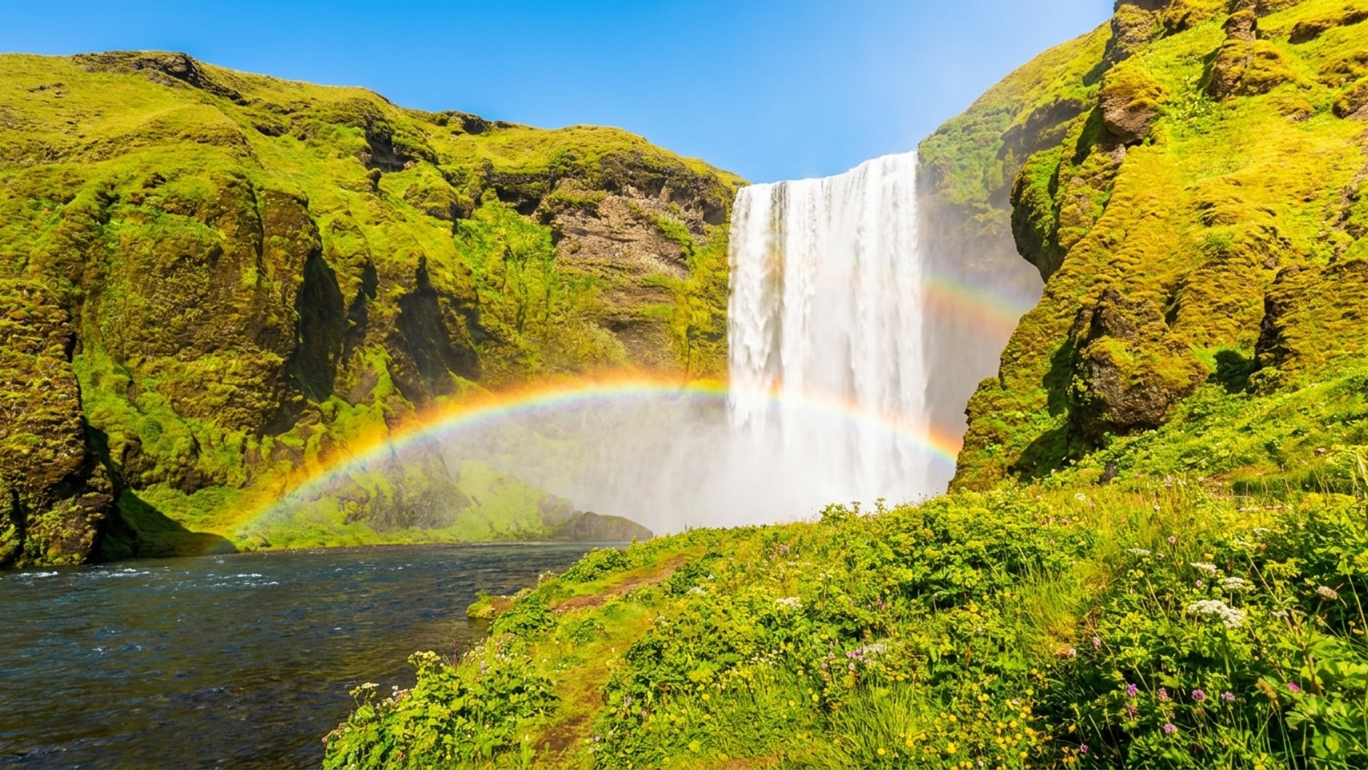 Skogafoss Wasserfall auf Island mit moosbewachsenen Klippen und Regenbogen